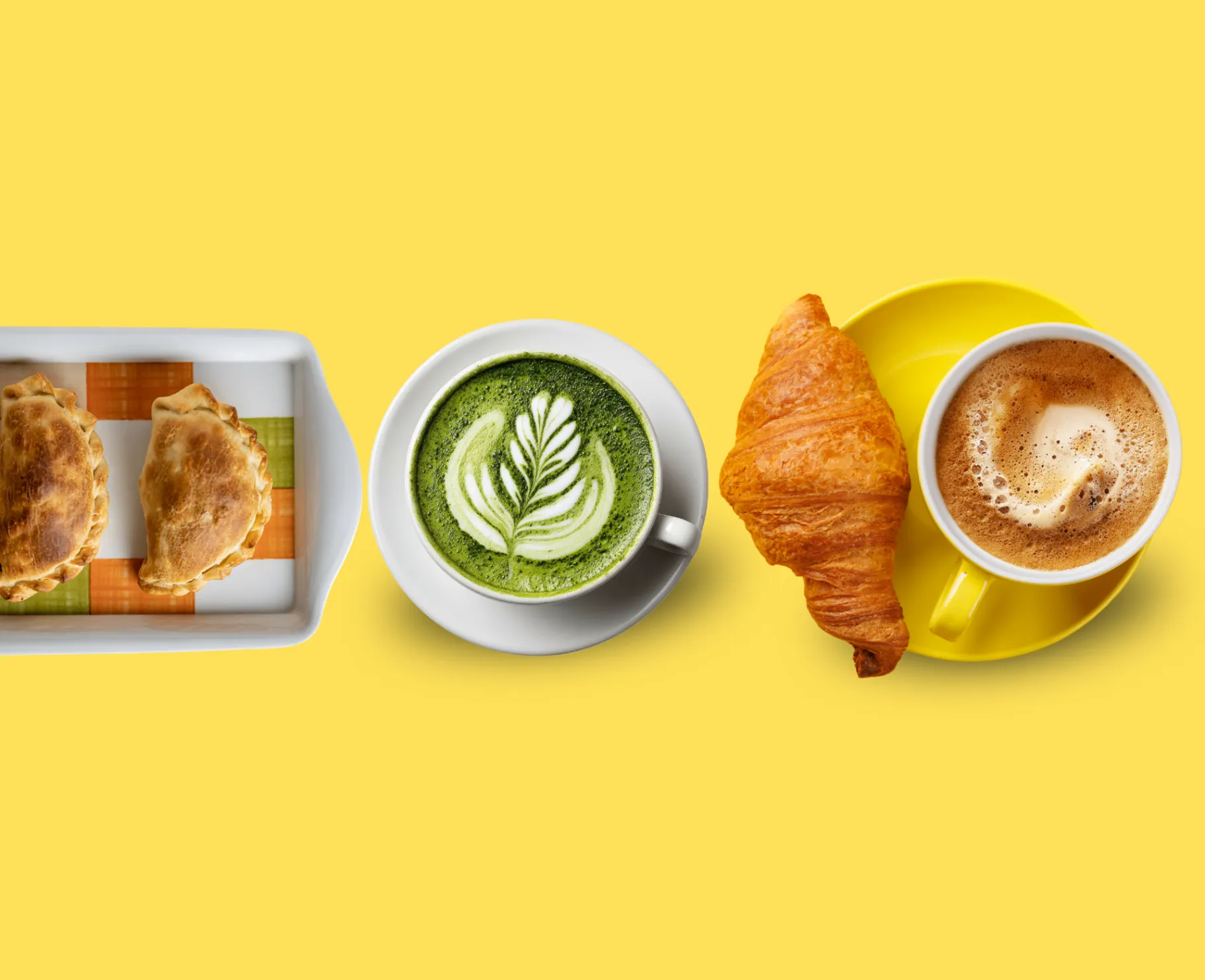 Empanadas, matcha latte, croissant, and coffee arranged on a yellow background.